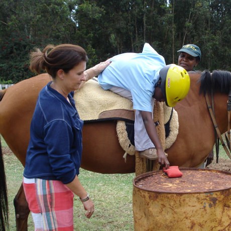Sidewalker helping a child perform exercises on a horse.